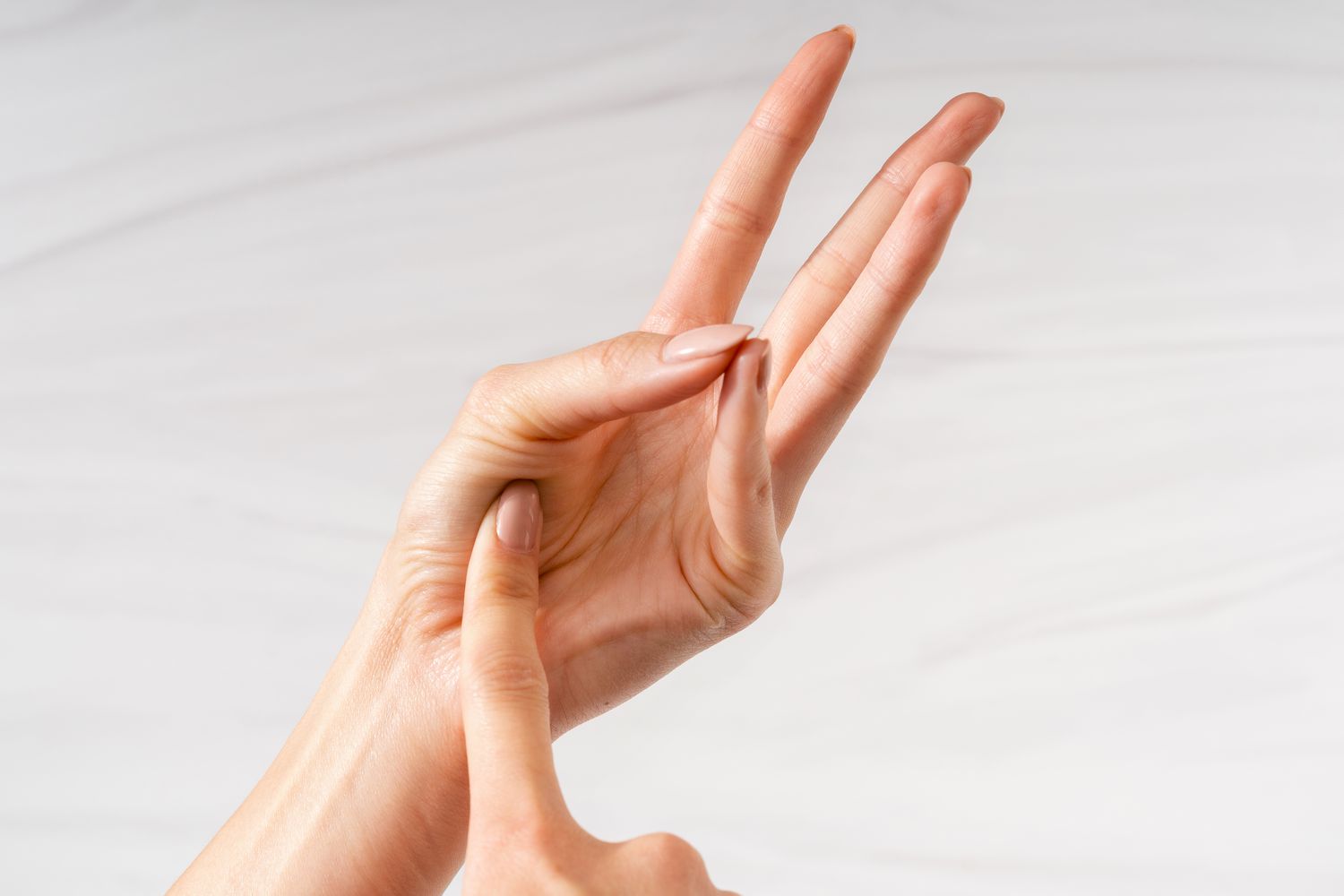 A finger touching the palm of a partially closed hand to demonstrate well done using The Finger Test to Check the Doneness of Meat