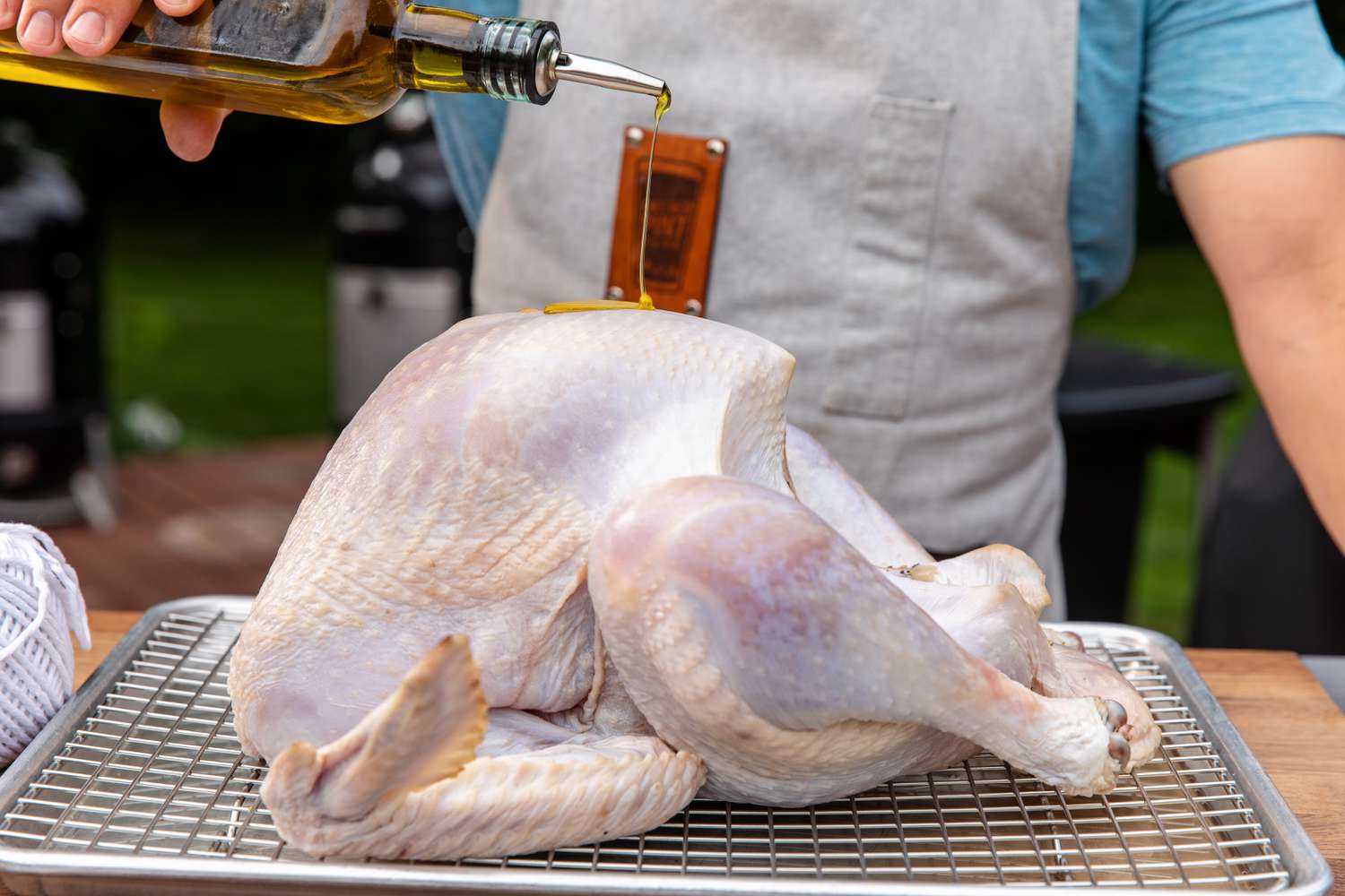 Coating a turkey with olive oil to make a brined smoked turkey.