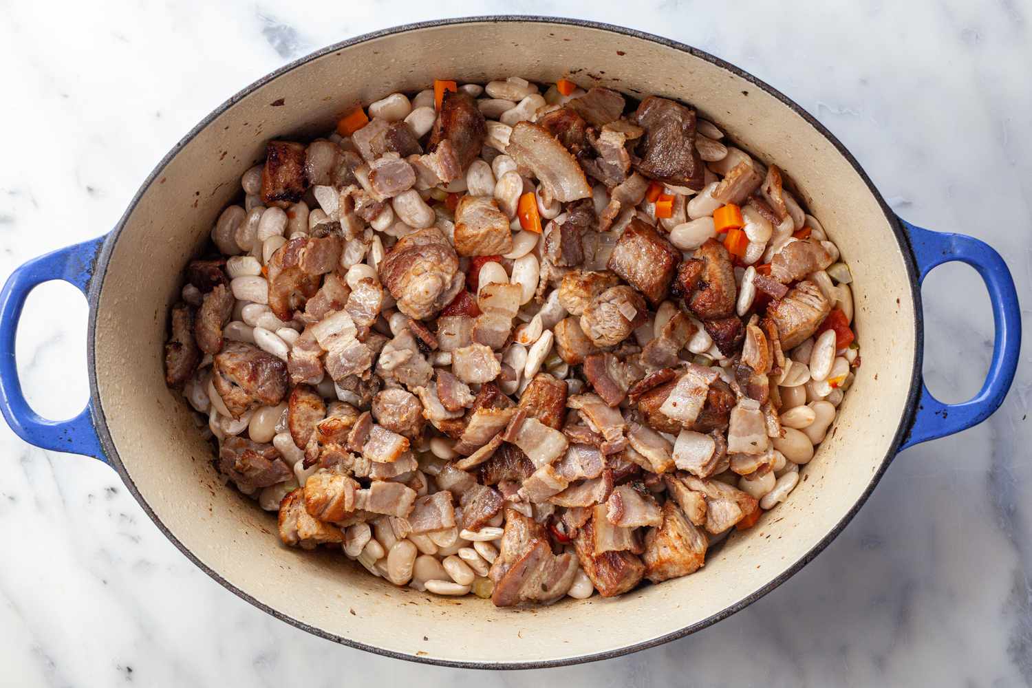 Add bacon, pork, and sausages to Dutch oven.