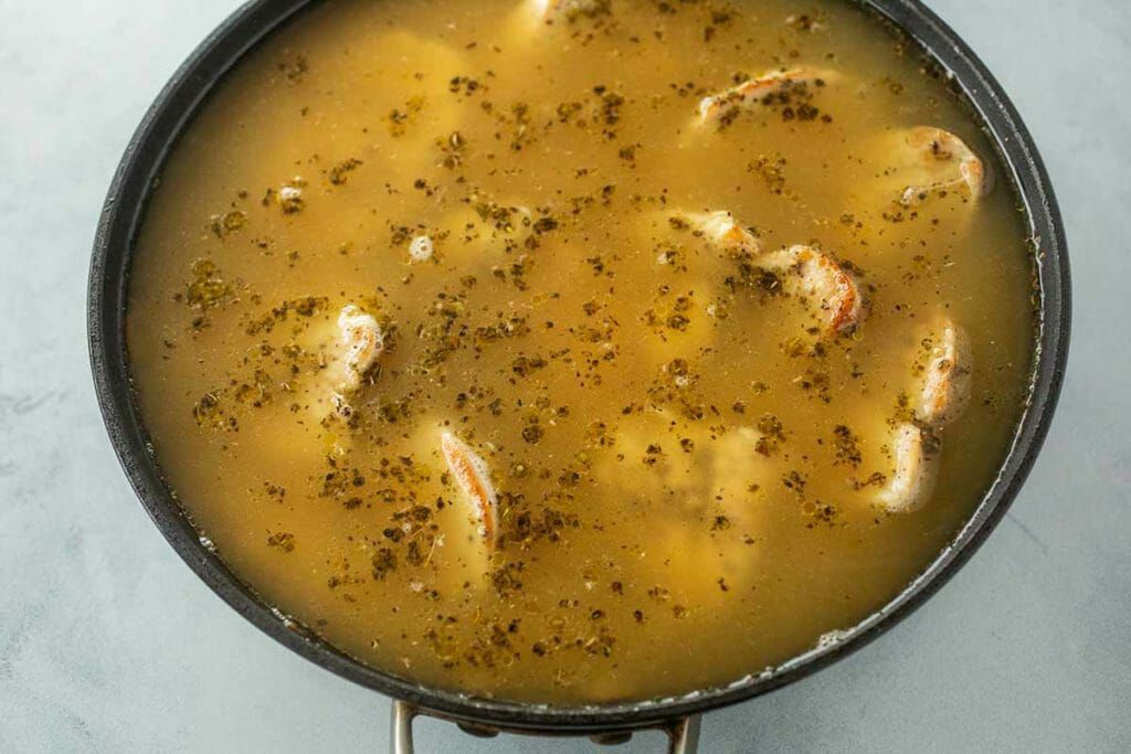 Chicken basting in broth for skillet chicken and rice