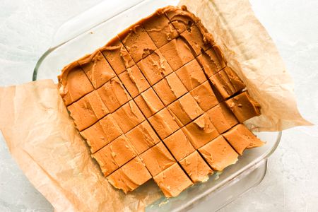Over head view of a peanut butter fudge cut up in squares in a glass baking dish