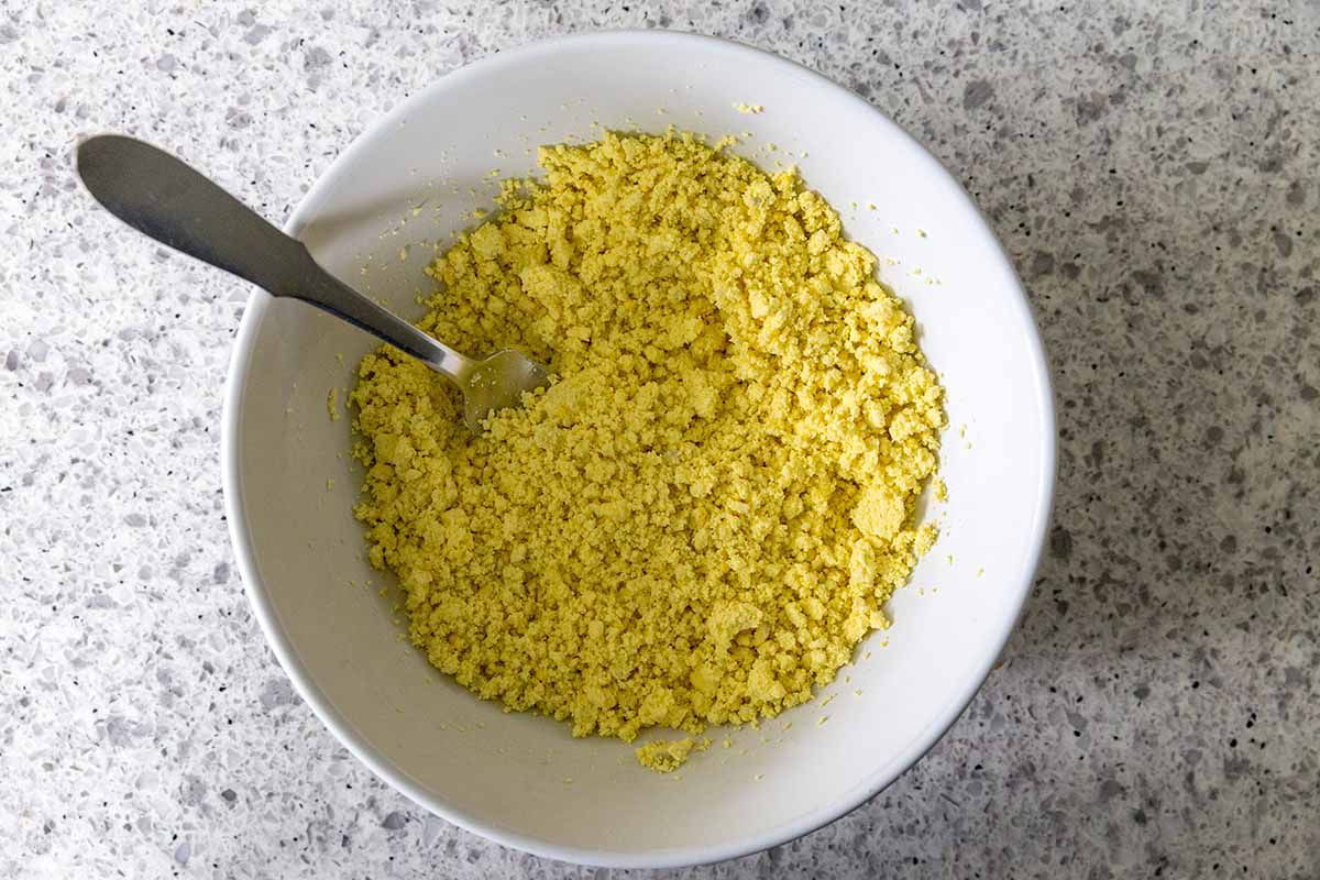 How to Make Deviled Eggs -- crumbled egg yolks stirred together in a white bowl with a spoon