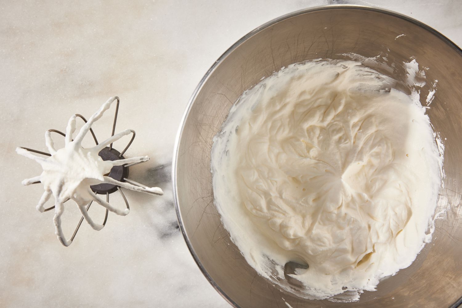 whipped cream in a mixer bowl next to a whisk attachment with more whipped cream for strawberry marlow recipe