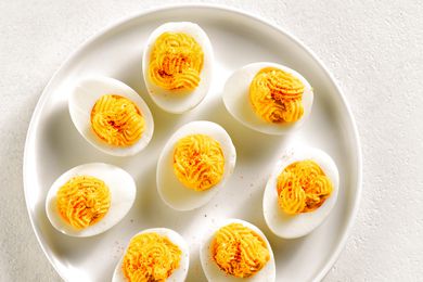 Overhead view of deviled eggs with paprika, mustard and mayonnaise on plate over white stone background.