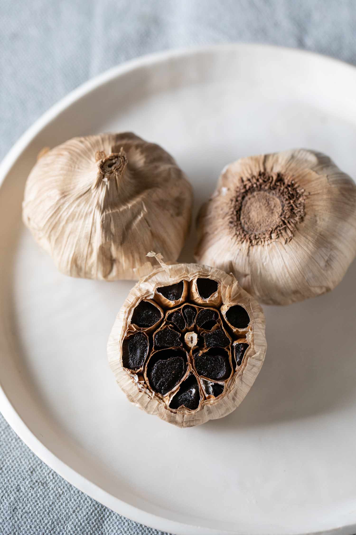 Three heads of black garlic on a plate.