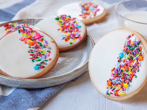 Royal icing and sprinkles decorate circle sugar cookies.