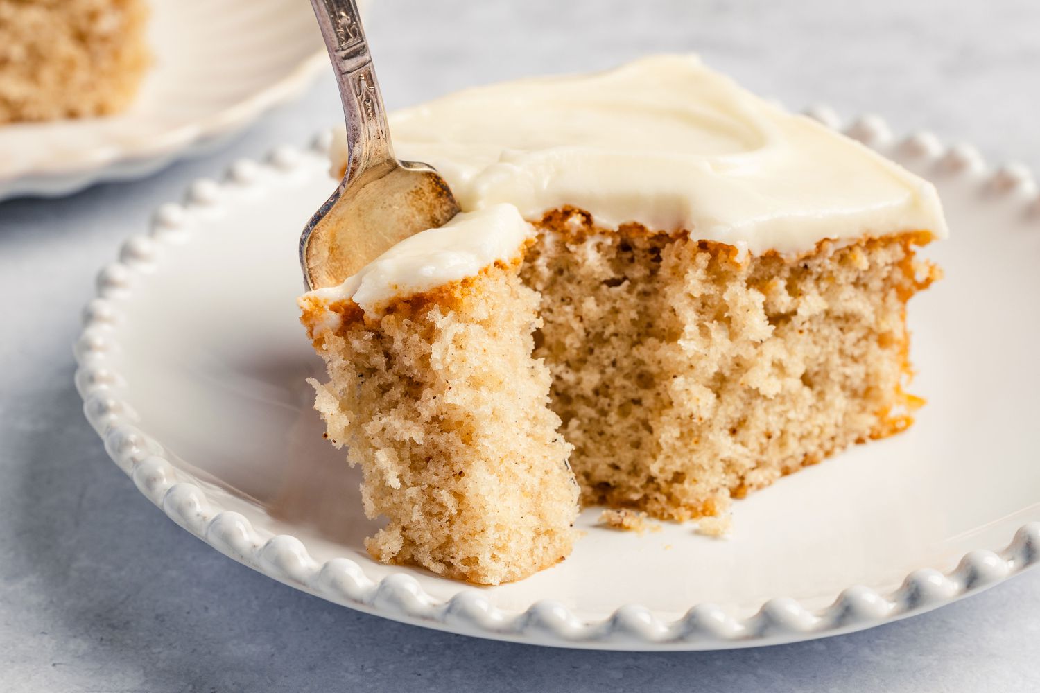 square slice of Feather Cake on a plate with a fork with a small bite portion on it