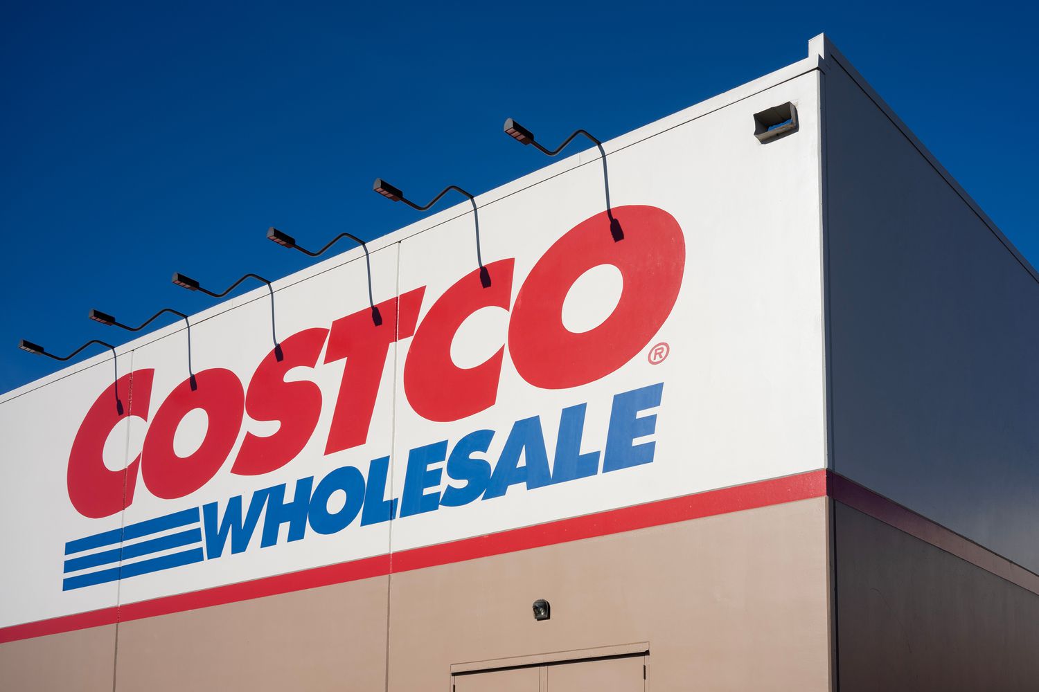 The facade of a Costco Wholesale store under a clear sky, focusing on the logo prominently displayed on the building