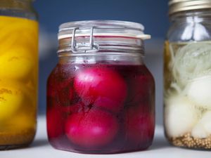 Three jars of pickled eggs; the middle jar includes pickle juice for bright pink eggs