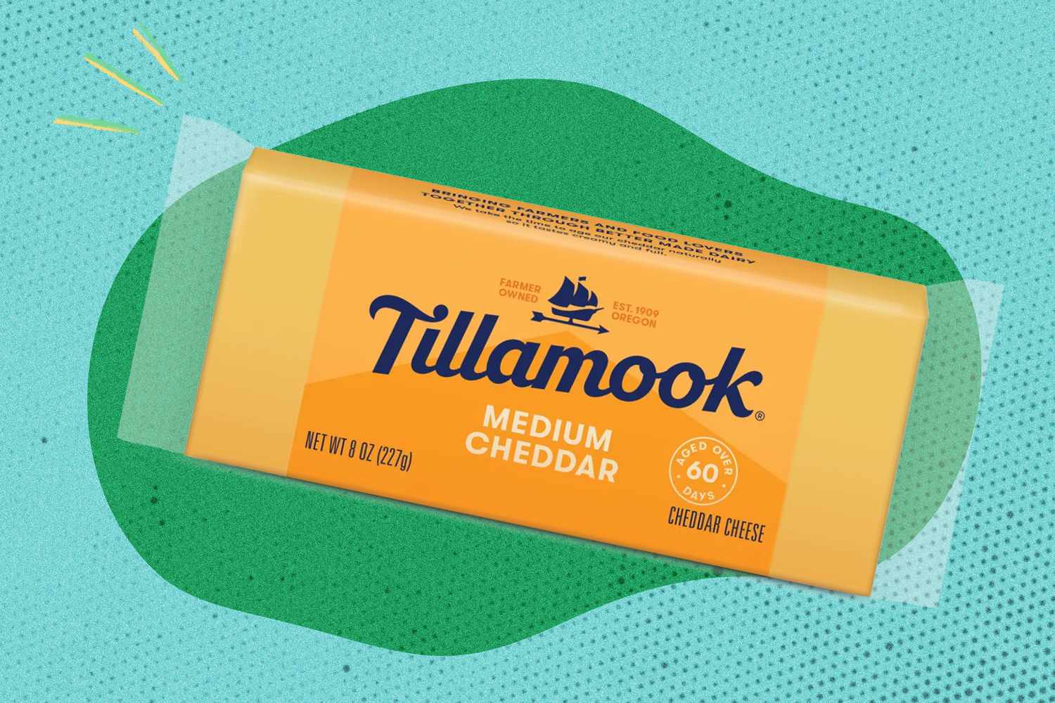 Eight ounce package of Tillamook Medium Cheddar cheese on a green and blue speckled background
