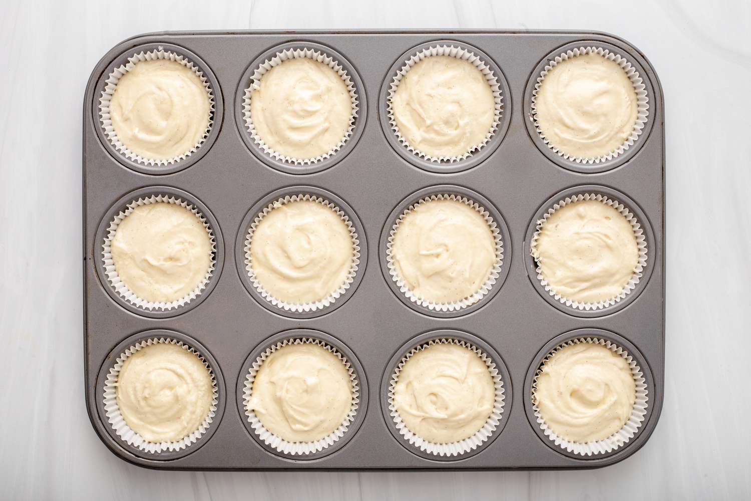 Batter in a muffin tin to show how to make cupcakes.