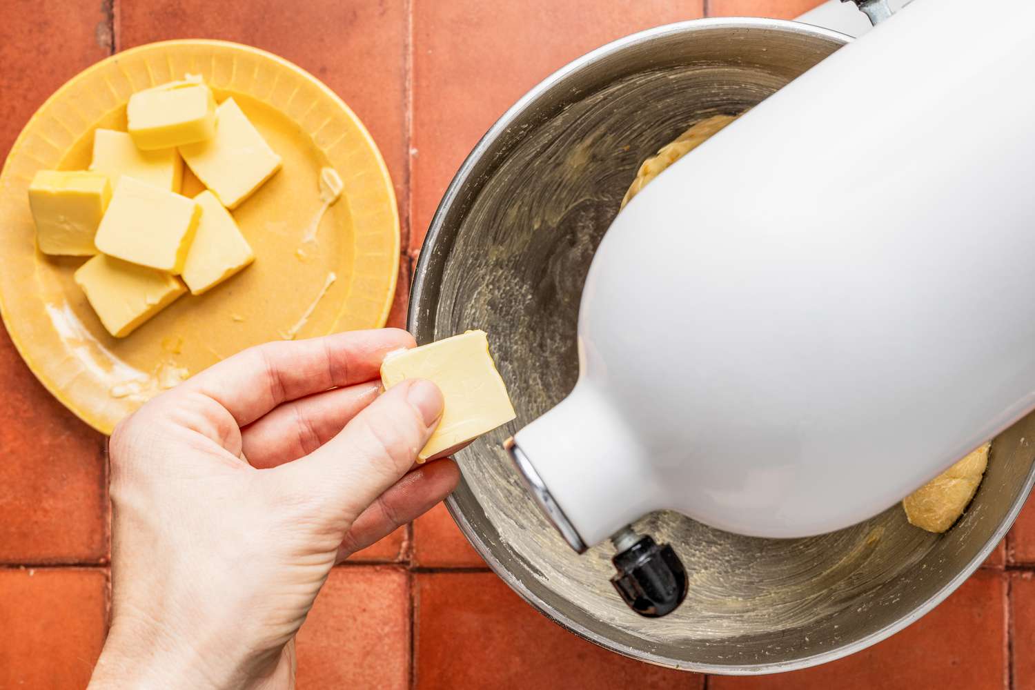 Pieces of butter added to a stand mixer as pan de muerto ingredients are mixed together