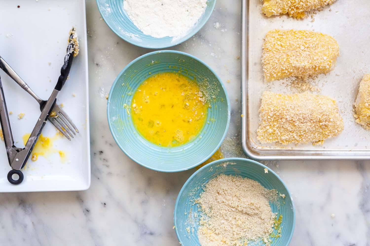 Fish fillets on a baking sheet to make Crispy Oven Baked Fish Sandwiches with Mayo and Tangy Pickled Onions.