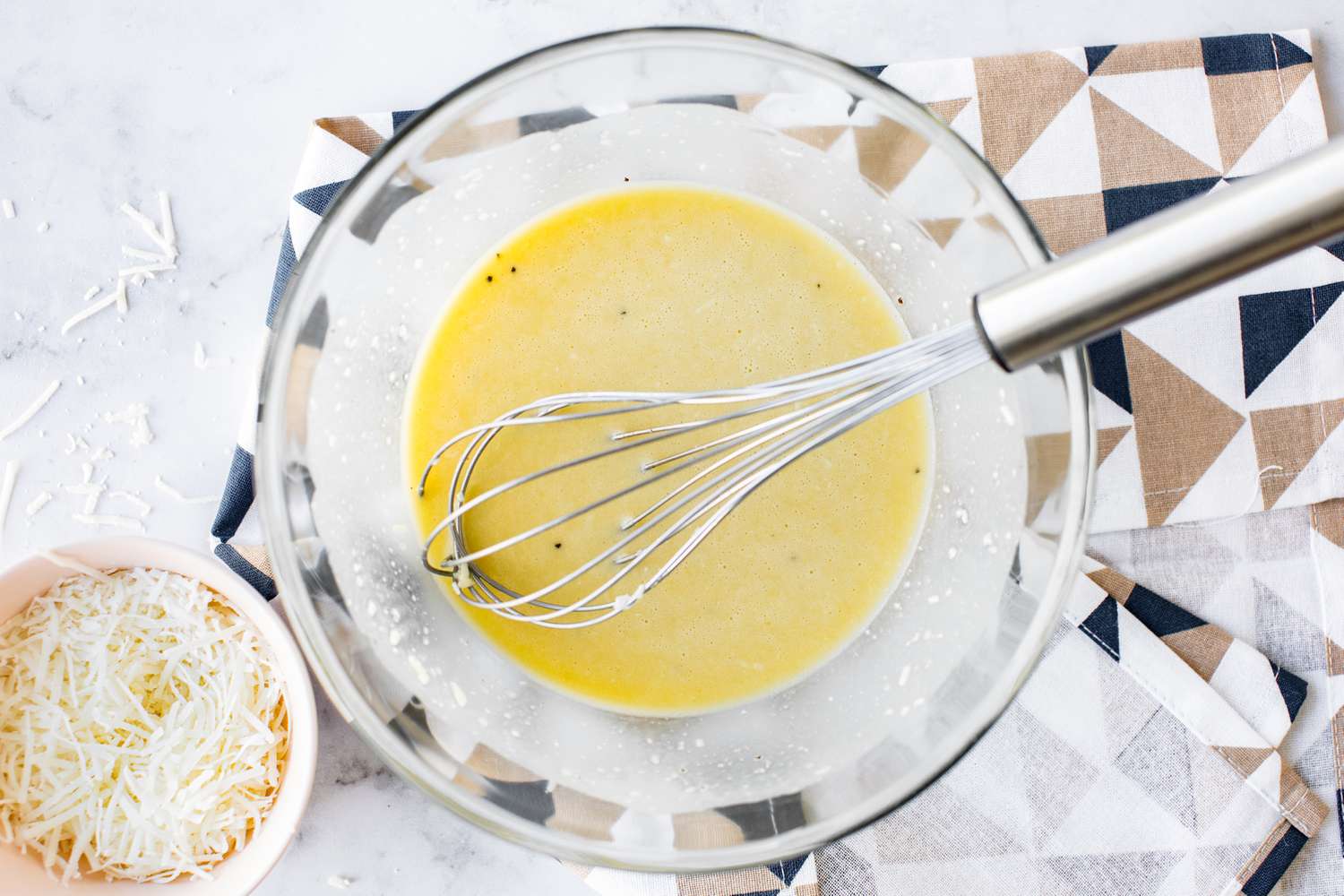 Bowl of Caesar Dressing Whisked Together and Next to it a Bowl of Parmesan
