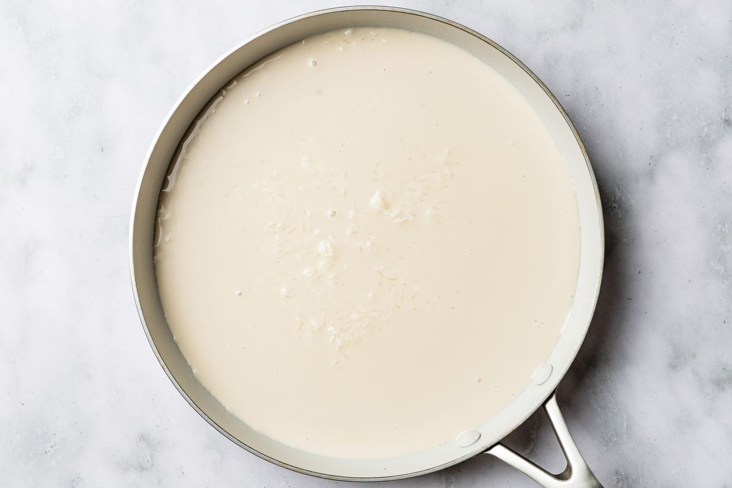 coconut cream, sugar, and rice boiling in a pan for biko (Filipino sticky rice cake) recipe