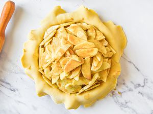 An apple pie before baking, on a marble countertop
