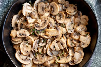 A bowl of sauted sliced mushrooms with herbs