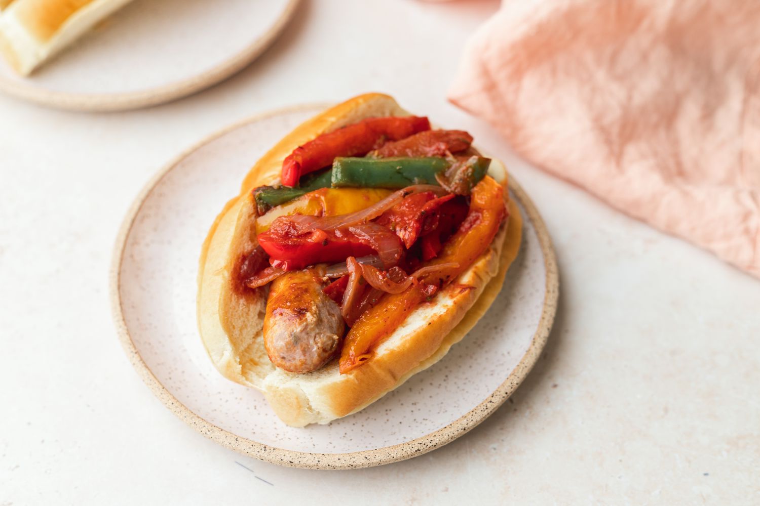 Italian sausage and peppers in a hoagie served on a white plate