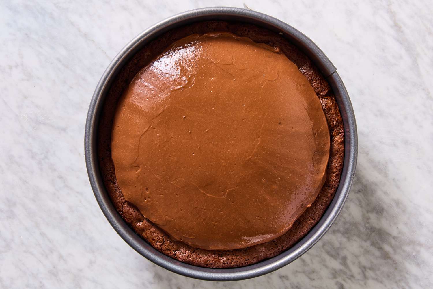 Overhead view of a springform pan with the pudding added to the baked crust and brownie batter for Mississippi Mud Pie recipe