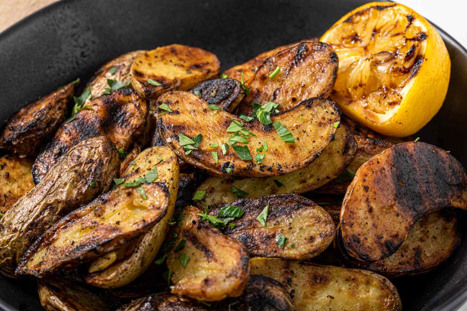Grilled Fingerling Potatoes and a Grilled Halved Lemon in a Black Bowl