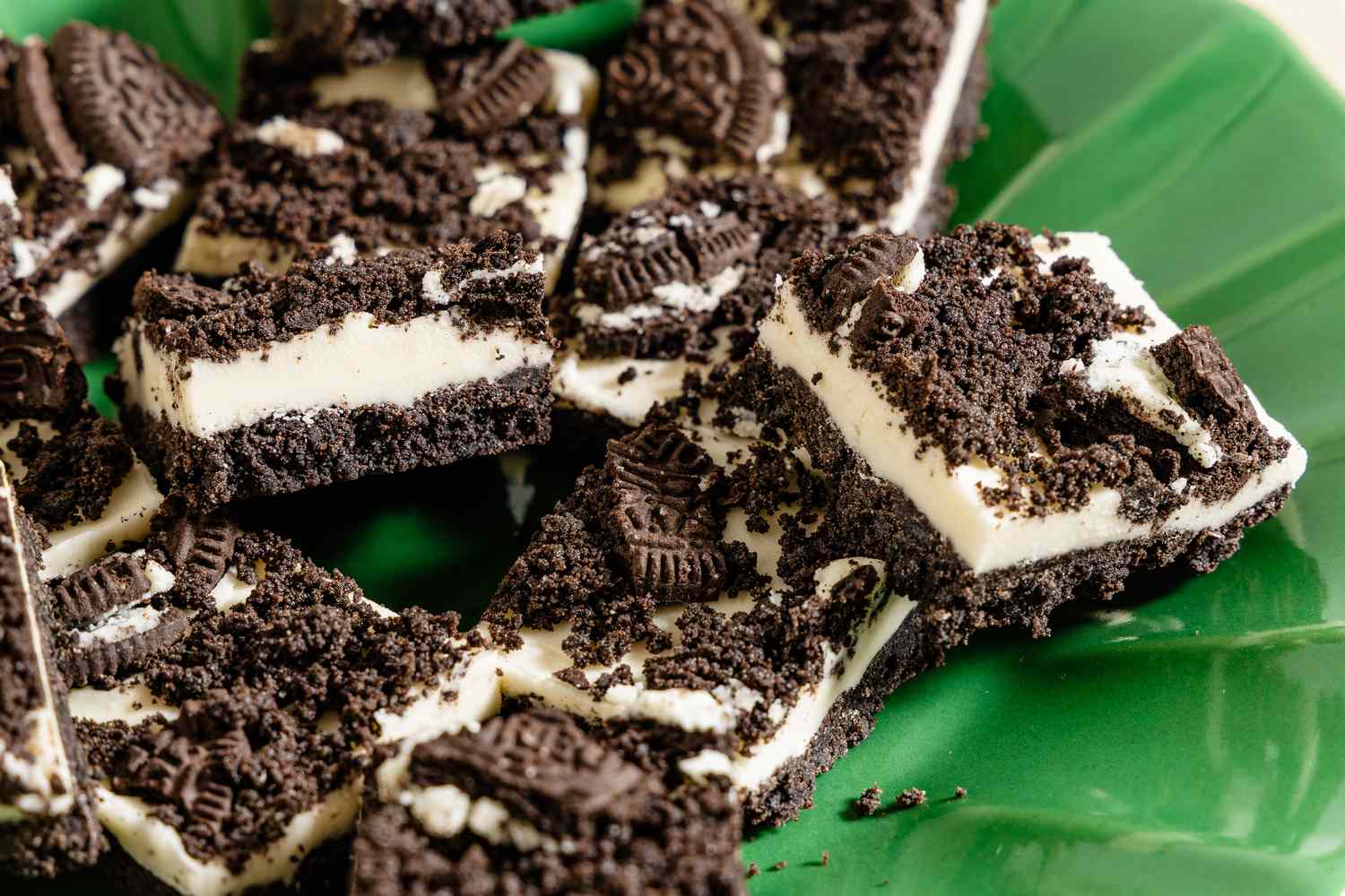 Dessert bars topped with crumbled cookies displayed on a green plate