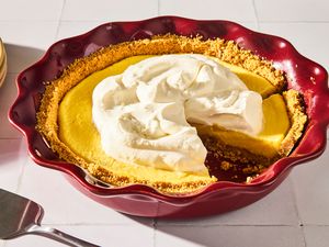 Pie with a whipped cream topping in a red dish and a slice missing