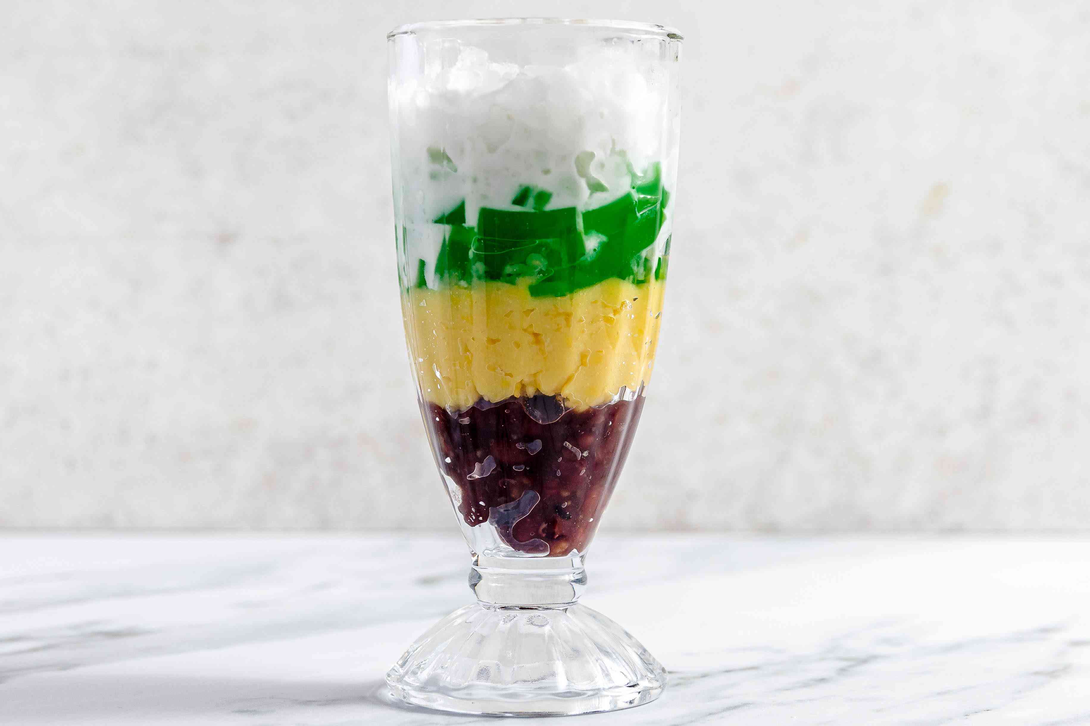 Glass of Che Ba Mau (Layers From Bottom to Top: Reed Bean Paste, Mung Beans, Pandan Jelly, Crushed Ice, and Coconut Sauce)