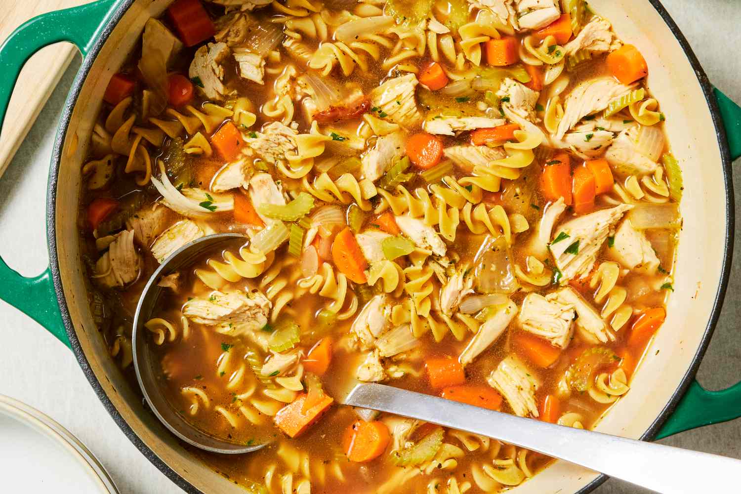 Turkey noodle soup with vegetables in a green pot