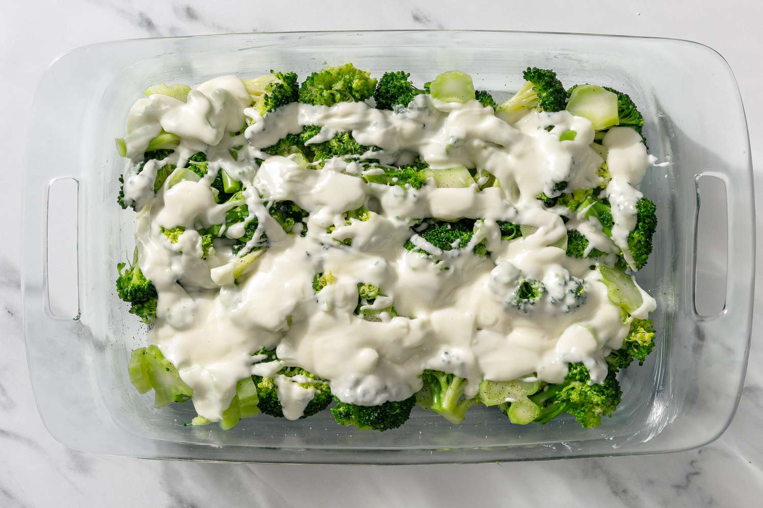 broccoli topped with creamy mixture in a casserole dish for My Mom’s Famous Broccoli Cheese Casserole