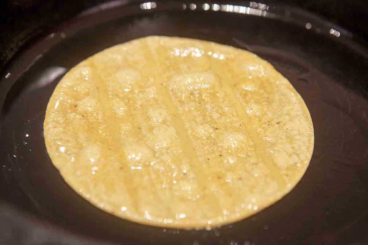 tortilla being fried in oil in skillet