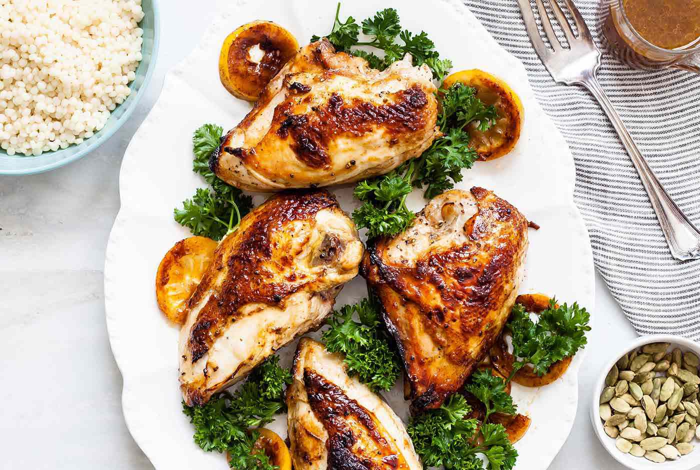 cardamom honey chicken with greens on a white plate with side dishes