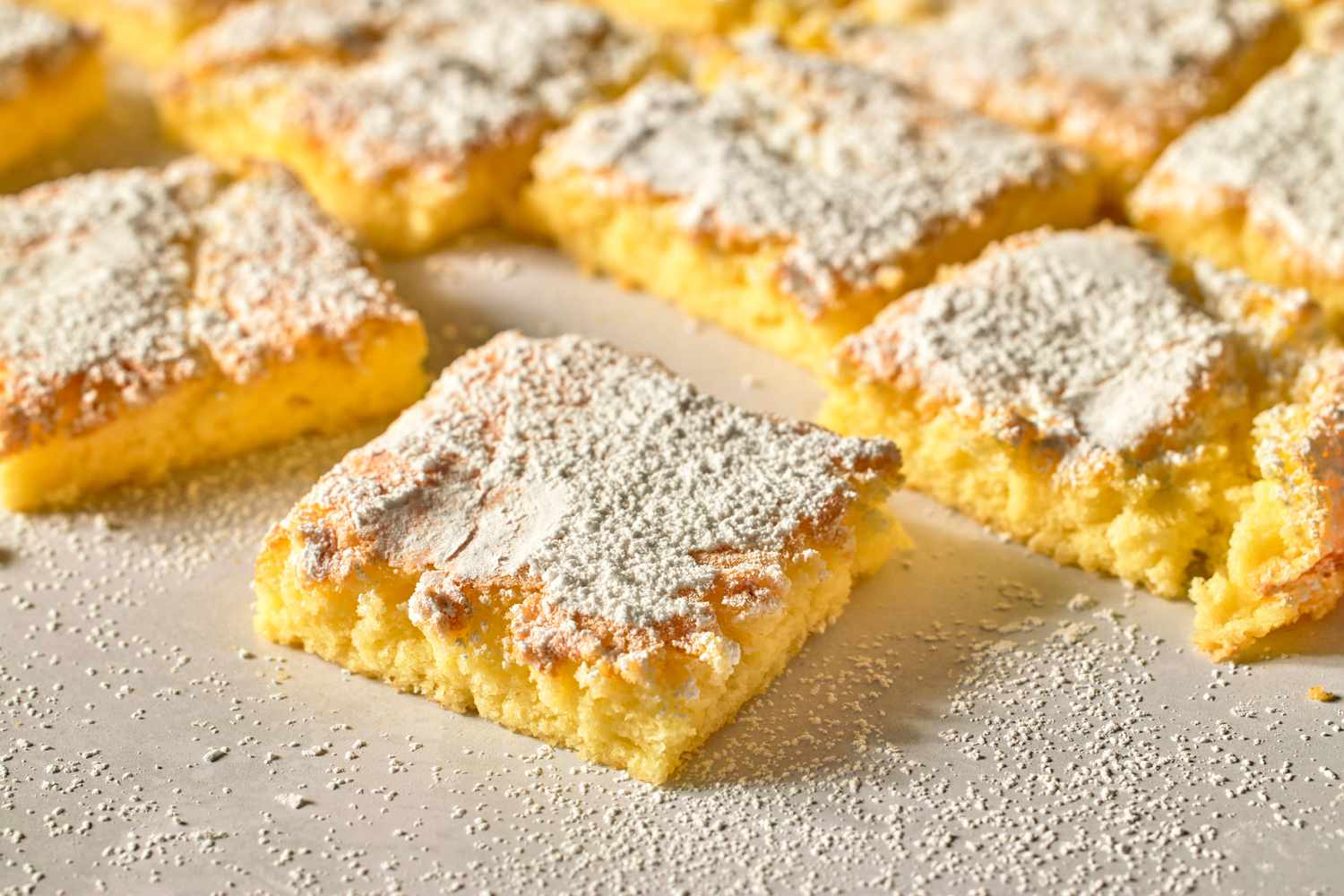 Squares of powdered sugar topped bar dessert arranged closely