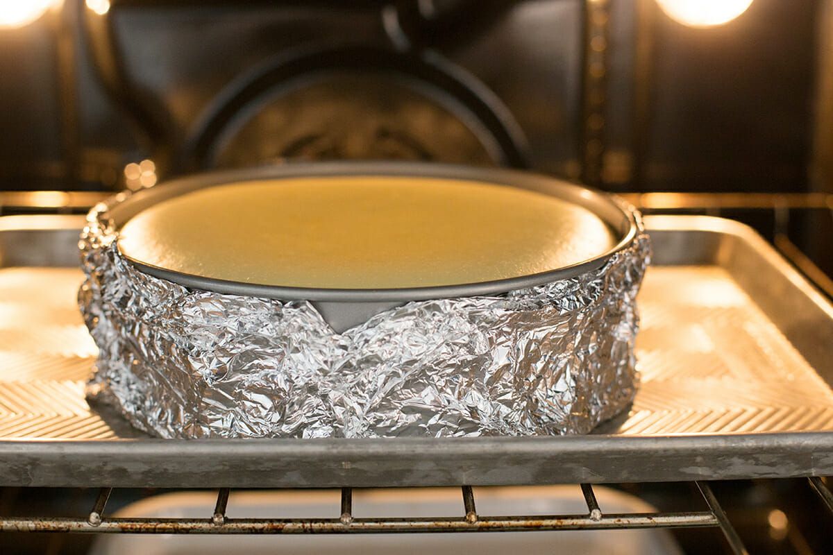 Lemon cheesecake in the oven wrapped in foil and set on a baking sheet
