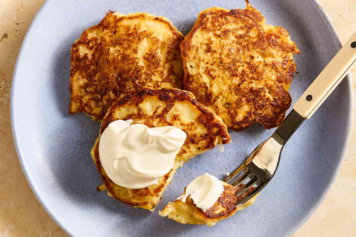 Overhead view of a plate of of Irish Boxty with one topped with butter next to a fork holding a bite all on a stone countertop