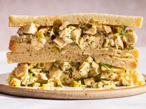 A chicken salad sandwich cut in half displayed on a plate