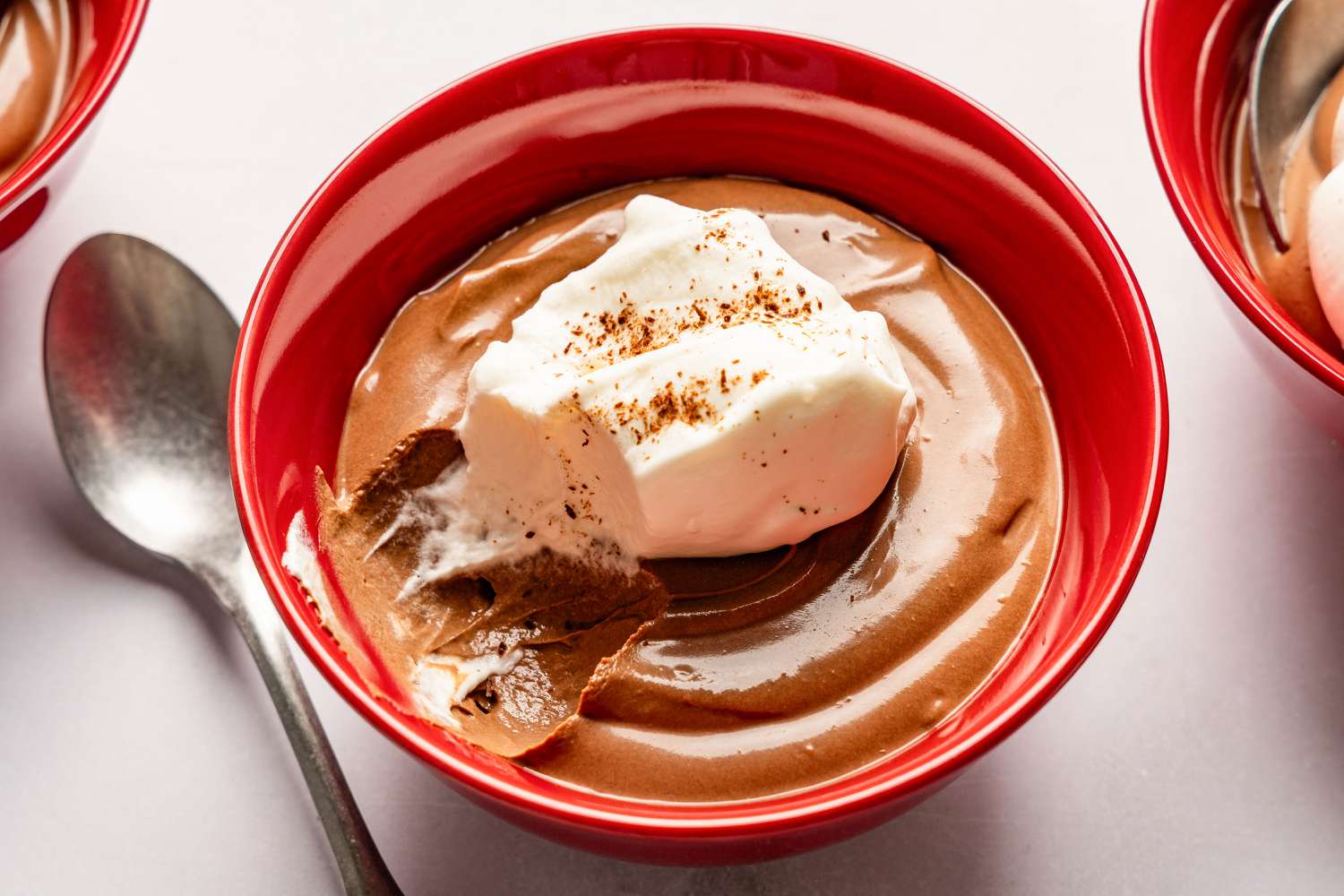 2-Ingredient Chocolate Pudding in a bowl topped with whipped cream and cocoa powder, spoon on the side
