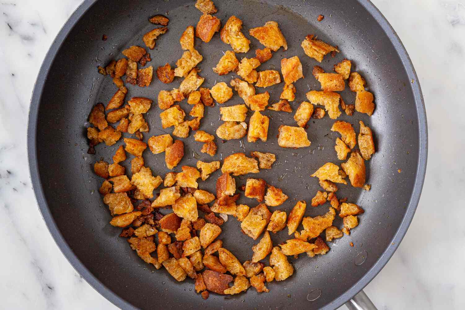 Frying cubed bread in a skillet for Spanish Style Migas with Asparagus, Chorizo, Bacon, and Eggs.