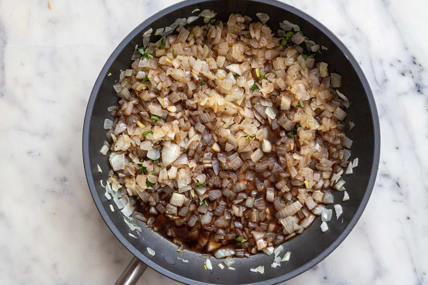 Making an onion jam recipe with balsamic vinegar by sauteeing onions in a skillet.