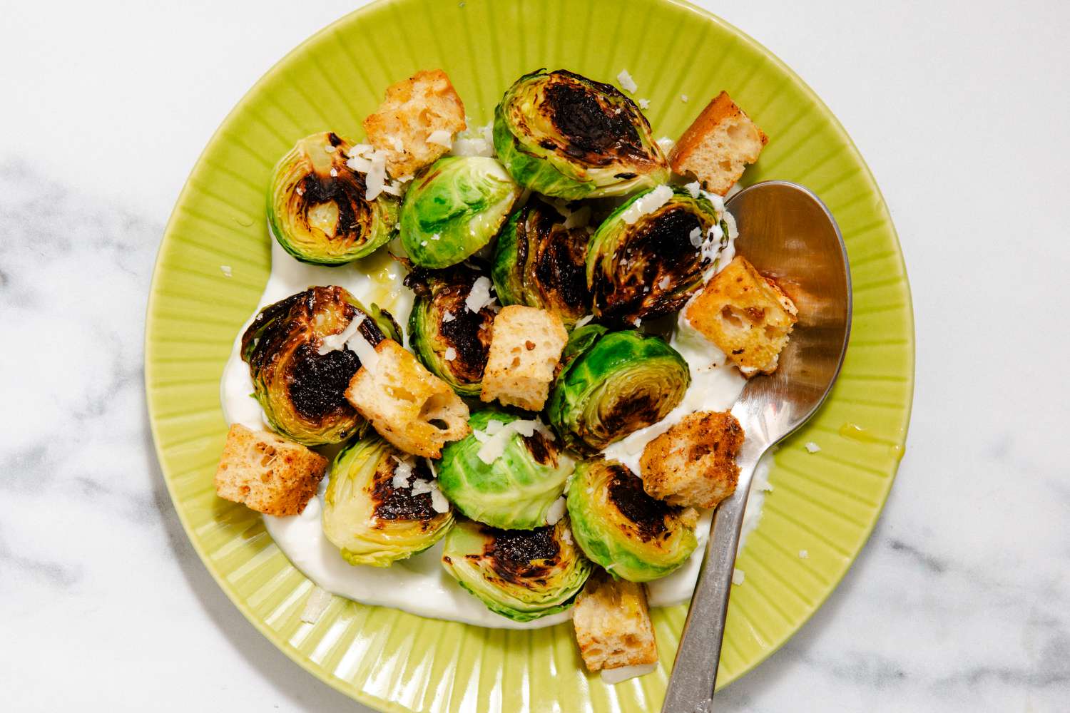 Charred Brussels sprouts and croutons on a bed of yogurt on a plate