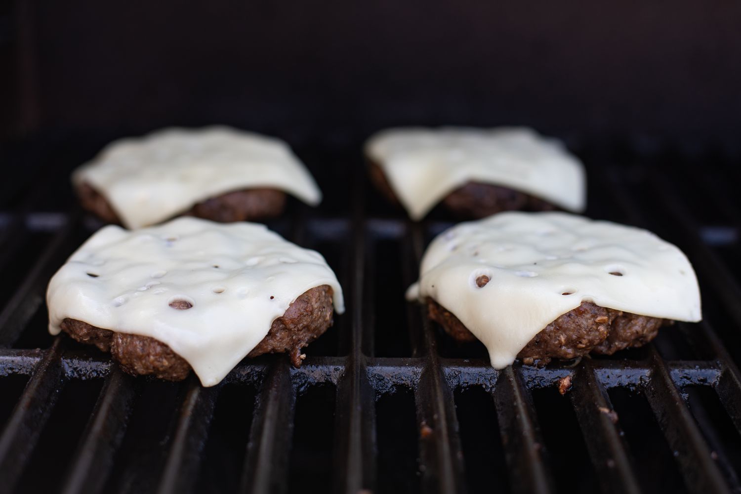Mushroom swiss burgers topped with cheese on the grill.