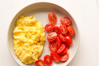 Scrambled eggs and halved cherry tomatoes arranged on a plate