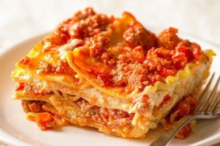 A slice of lasagna on a plate with a fork