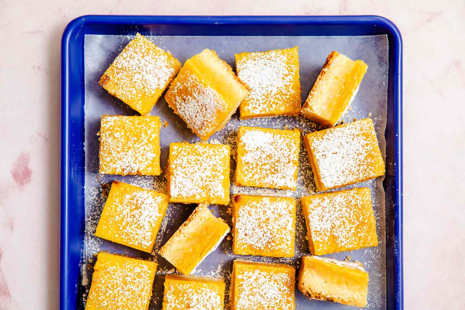 lemon bars on a parchment paper-lined baking sheet