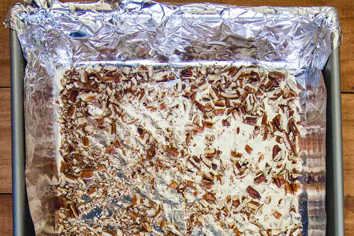 Chopped pecans on a foil covered baking sheet to make a Toffee Recipe.