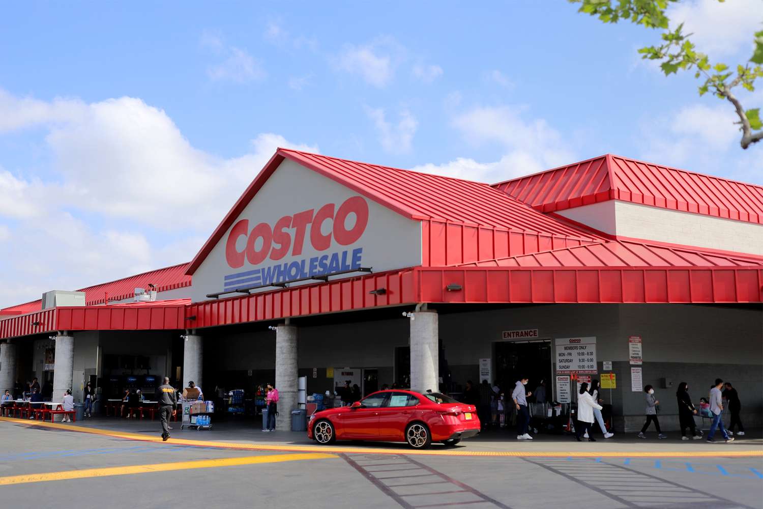 Entrance of a Costco Wholesale store showing people and a car in the front area
