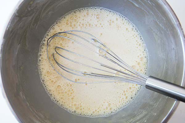 Cherry clafoutis batter in bowl with whisk