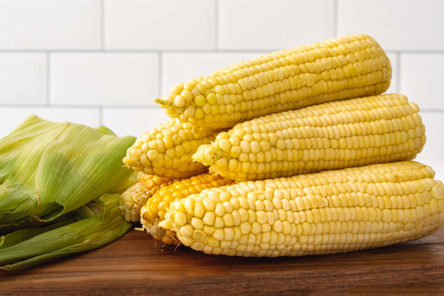 Stacked microwave corn on a cutting board.