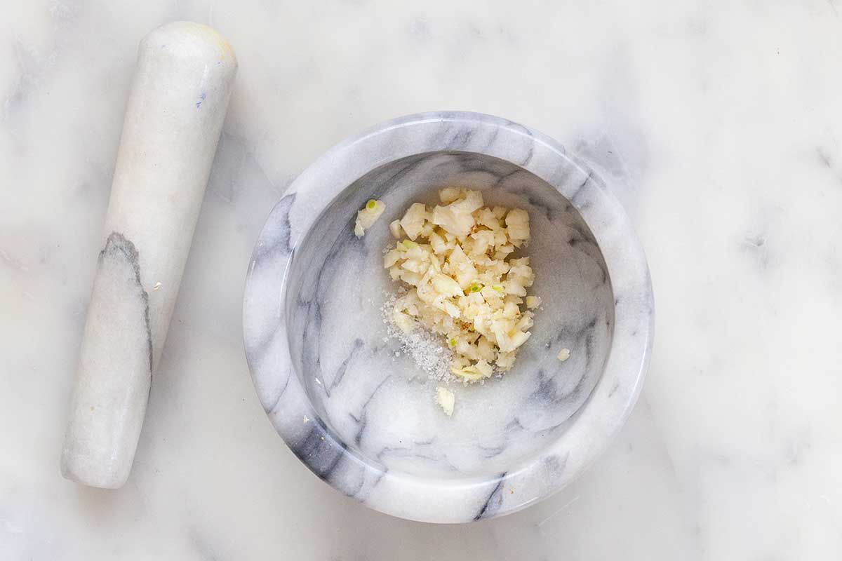 Garlic cloves and salt in a pestle and mortar.