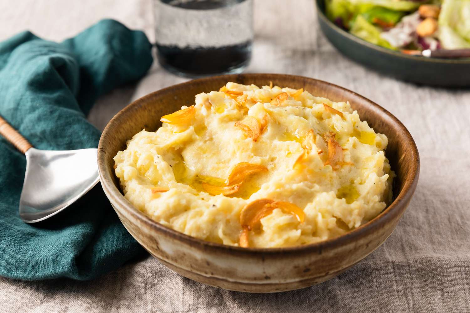 Too Much Garlic Mashed Potatoes in a brown bowl with a spoon on the side