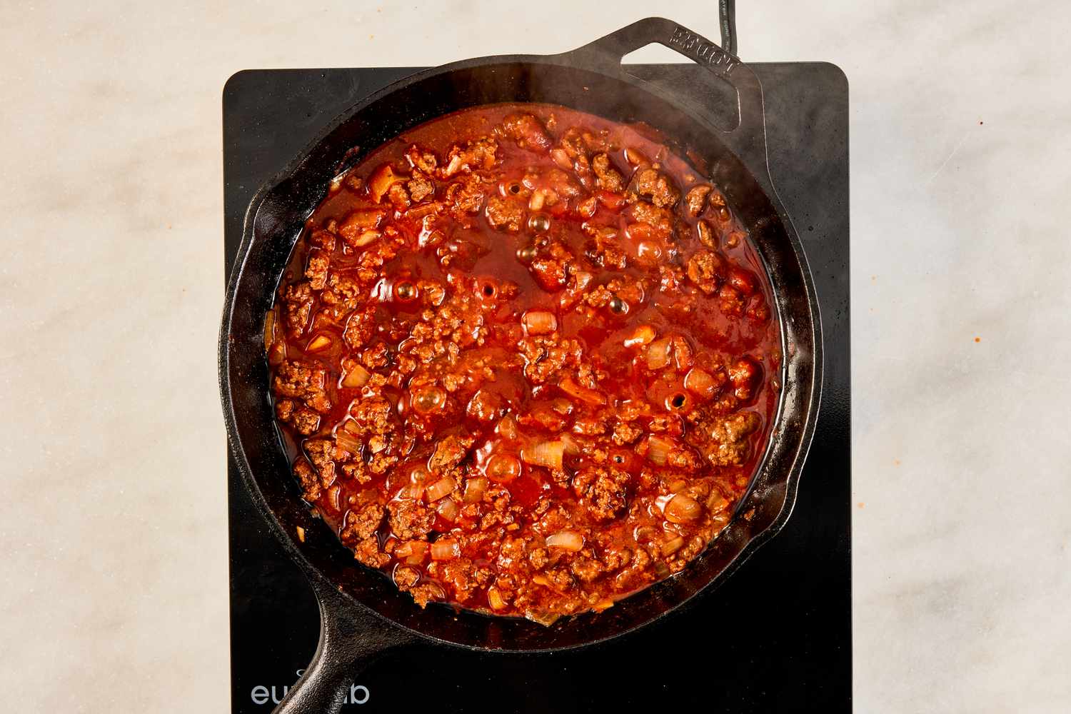 tomato sauce added to cooked ground beef in the cast iron skillet for crispy ground beef recipe 